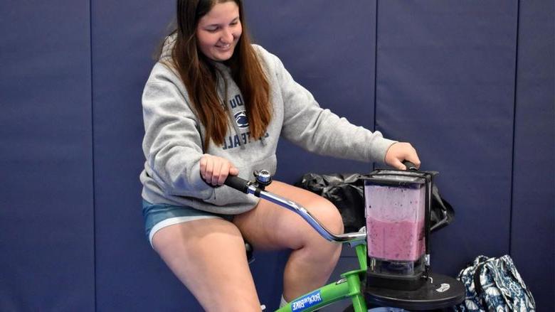 365英国上市杜波依斯分校 student Aleigha Geer pedals the smoothie bike during the 2023 Earth Day celebration at the PAW Center.